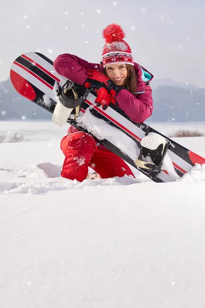 Snowboarderin posiert auf Schnee lizenzfreie Stockfotos