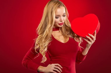 Kırmızı kalp şeklinde hediye kutusu tutan kız