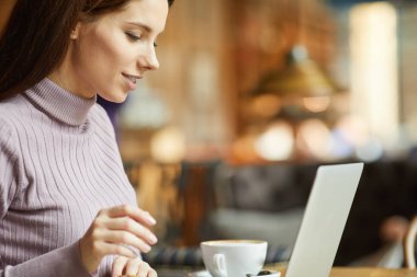 Güzel esmer kafede dizüstü bilgisayar kullanarak