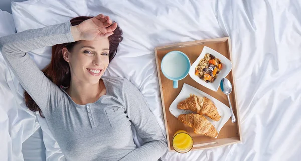 Счастливая брюнетка завтракает в постели — стоковое фото