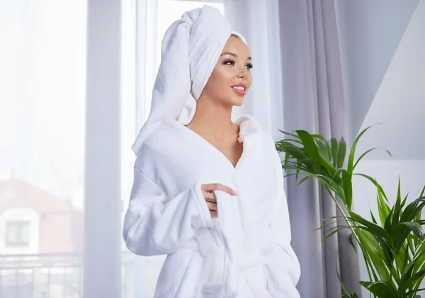 Uma mulher de roupão de banho e uma toalha — Fotografia de Stock