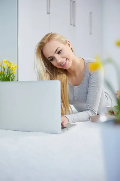 Χαμογελαστή γυναίκα που βρίσκεται στην κουβέρτα χρησιμοποιώντας το laptop — Φωτογραφία Αρχείου