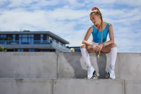 Gorgeous blond girl in a swimsuit on roller skates sitting in a — Stock Photo, Image