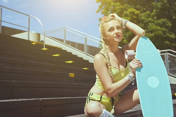 Bella giovane donna bionda con il suo longboard in città in s — Foto Stock