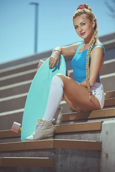 Beautiful young blonde woman with his longboard in the city in s — Stock Photo, Image