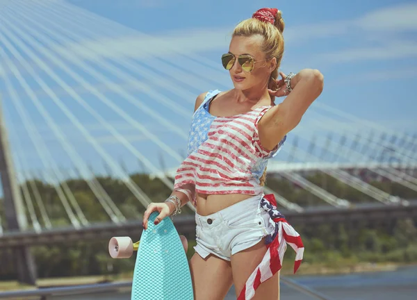 Beautiful young blonde woman with his longboard in the city in s — Stock Photo, Image