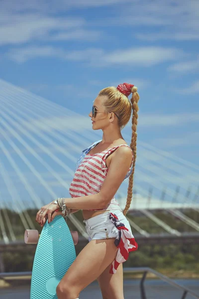 Beautiful young blonde woman with his longboard in the city in s — Stock Photo, Image