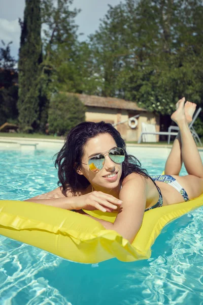 Woman in bikini sunbathing on air mattress — Stock Photo, Image