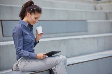 İşkadını bir tablet ile beton duvara oturur. 