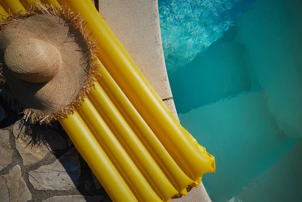 El colchón y el sombrero se encuentran en el borde de la piscina . — Foto de Stock