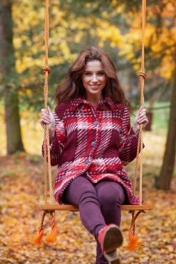 Kadın bir salıncak bir sonbahar Park üzerinde