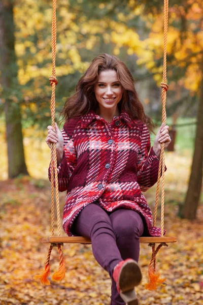 Kadın bir salıncak bir sonbahar Park üzerinde