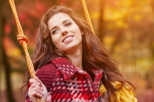 Vrouw op een schommel in een herfst park — Stockfoto