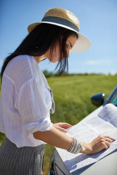 Mulher com mapa no carro verificando rota — Fotografia de Stock