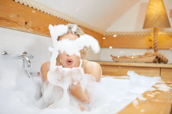 Mujer joven jugando con espuma en la bañera —  Fotos de Stock
