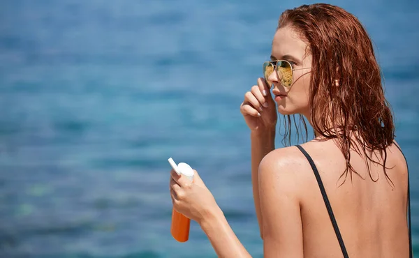 Młoda kobieta na plaży stosując krem z filtrem — Zdjęcie stockowe