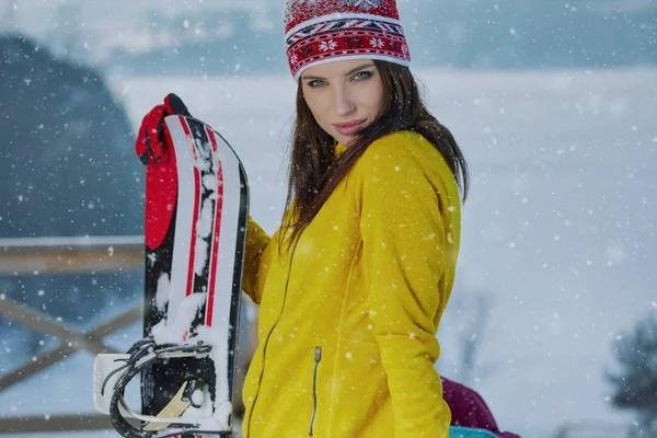 Sportig kvinna håller snowboard i bergen — Stockfoto