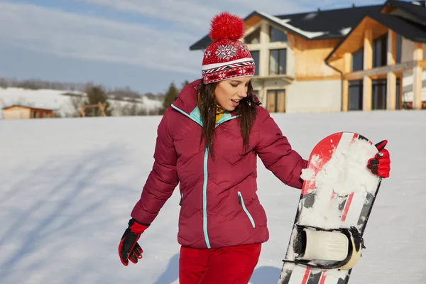 Deportiva hembra sostiene snowboard en montañas —  Fotos de Stock