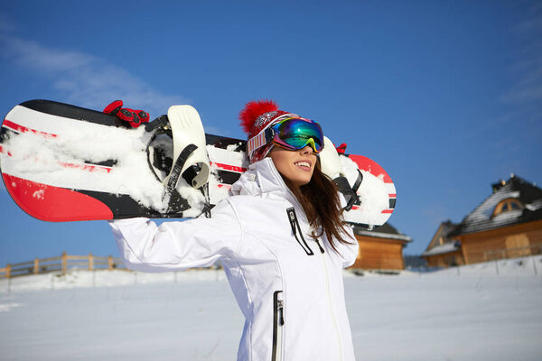 Sporty female holds snowboard in mountains