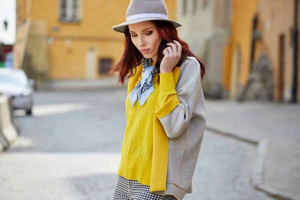 Modieuze vrouw in een hoed, zonnebril, gele trui, wandelen — Stockfoto