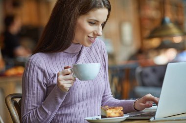 Güzel esmer kafede dizüstü bilgisayar kullanarak. Blogger iş kavramı