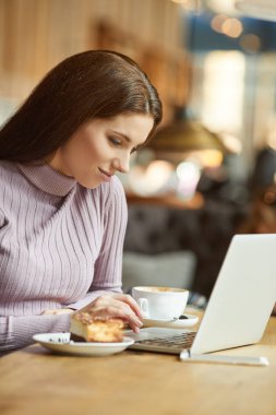 Güzel esmer kafede dizüstü bilgisayar kullanarak. Blogger iş kavramı