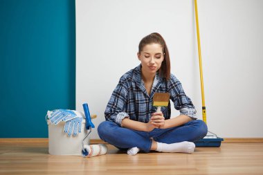 Mutlu güzel bir kadın duvar boyuyor.