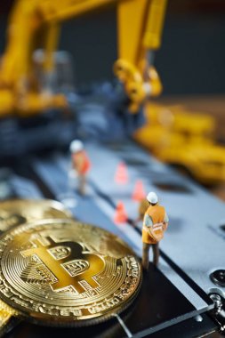 Küçük bir madenci altın sikke ile grafik kartı eşeliyor. Bitcoin madenciliği ve kripto para birimi kavramı.