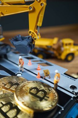 Küçük bir madenci altın sikke ile grafik kartı eşeliyor. Bitcoin madenciliği ve kripto para birimi kavramı.