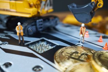 Küçük bir madenci altın sikke ile grafik kartı eşeliyor. Bitcoin madenciliği ve kripto para birimi kavramı.