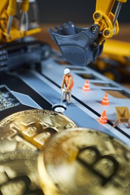Küçük bir madenci altın sikke ile grafik kartı eşeliyor. Bitcoin madenciliği ve kripto para birimi kavramı.