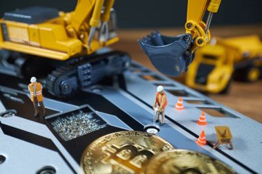 Küçük bir madenci altın sikke ile grafik kartı eşeliyor. Bitcoin madenciliği ve kripto para birimi kavramı.