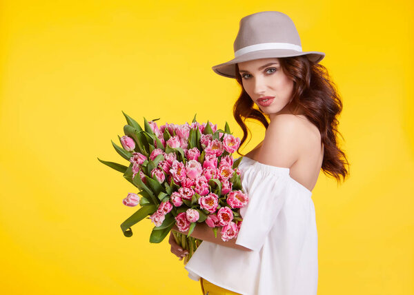 Spring girl iwith flowers tulips in hands on a light background
