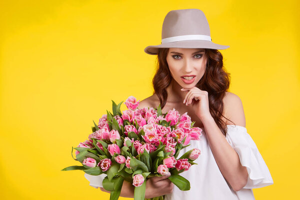 Spring girl iwith flowers tulips in hands on a light background