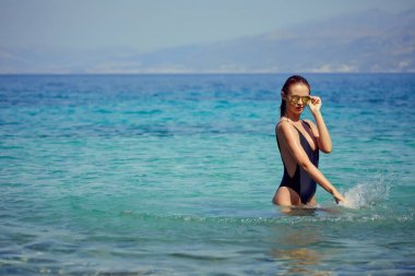 güzel bir genç kadın banyo ve mutlu tatil deniz sıçramasına bikini