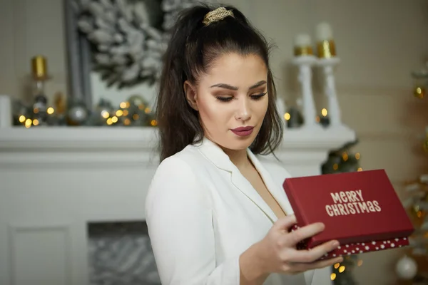 Sorrindo jovem com caixa de presente de Natal perto de natal tr — Fotografia de Stock