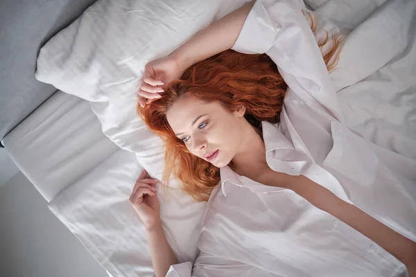 Πολύ αισθησιακή γυναίκα σε σέξι πόζα στο κρεβάτι με μακρύ φυσικό ερυθρά μαλλιά — Φωτογραφία Αρχείου