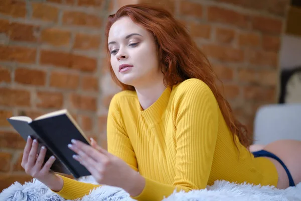Kızıl saçlı kadın evde kitap okuyor. — Stok fotoğraf