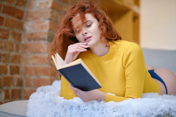 Donna dai capelli rossi legge un libro a casa — Foto Stock