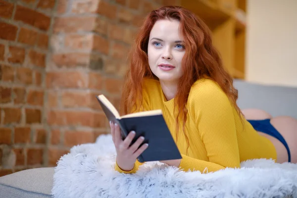 Rudowłosa kobieta czyta książkę w domu — Zdjęcie stockowe