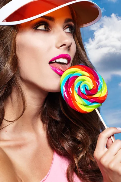 Girl wearing plastic cap holding lollipop — Stock Photo, Image