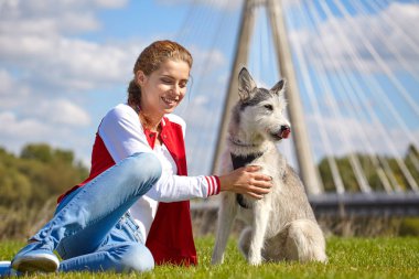 Şehrin bahçesinde köpeğiyle oynayan bir kadın.