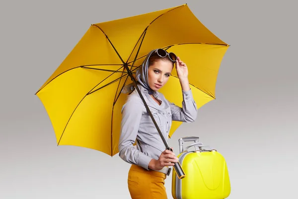Okouzlující žena se žlutým deštníkem a kufříkem. Cestovní koncept — Stock fotografie