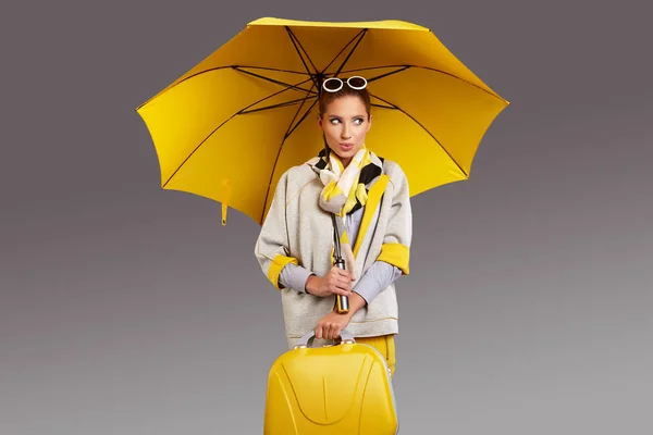 Glamour-Frau mit gelbem Regenschirm und Koffer. Reisekonzept — Stockfoto