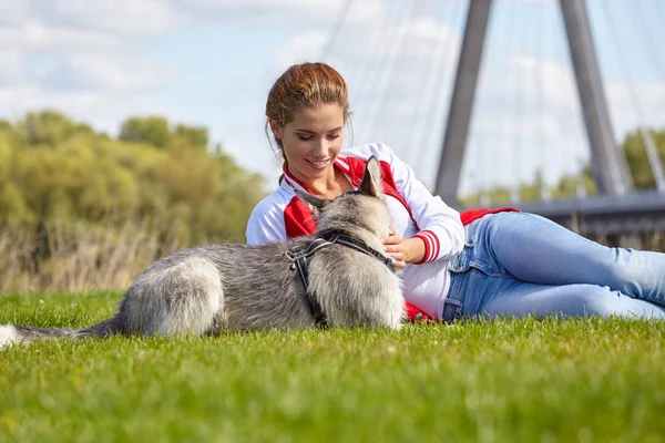 Женщина играет со своей собакой на городской лужайке — стоковое фото