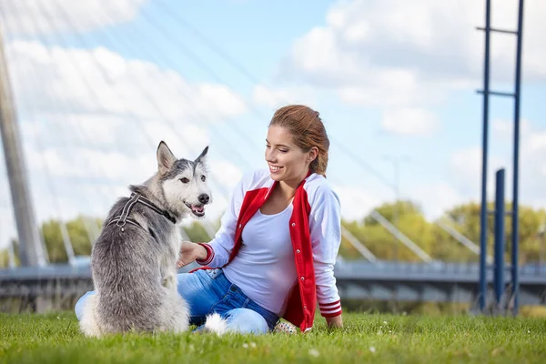 Mulher brincando com seu cão em um gramado da cidade — Fotografia de Stock