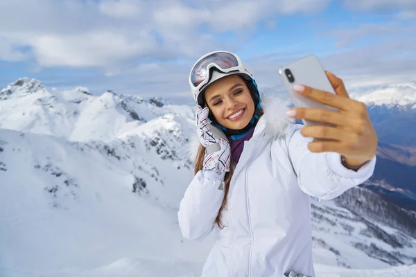 Menina faz uma selfie em roupas de esqui na montanha de neve . — Fotografia de Stock