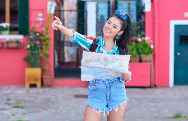 Ung lykkelig reisende kvinne som ser på turistkartet blant colo – stockfoto