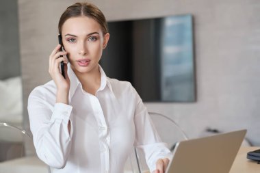 yatakta oturan bir dizüstü bilgisayar üzerinde çalışan rahat güzel kadın