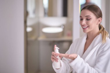 Güzel genç bir kadın banyodan sonra cildine vücut kremi sürüyor.